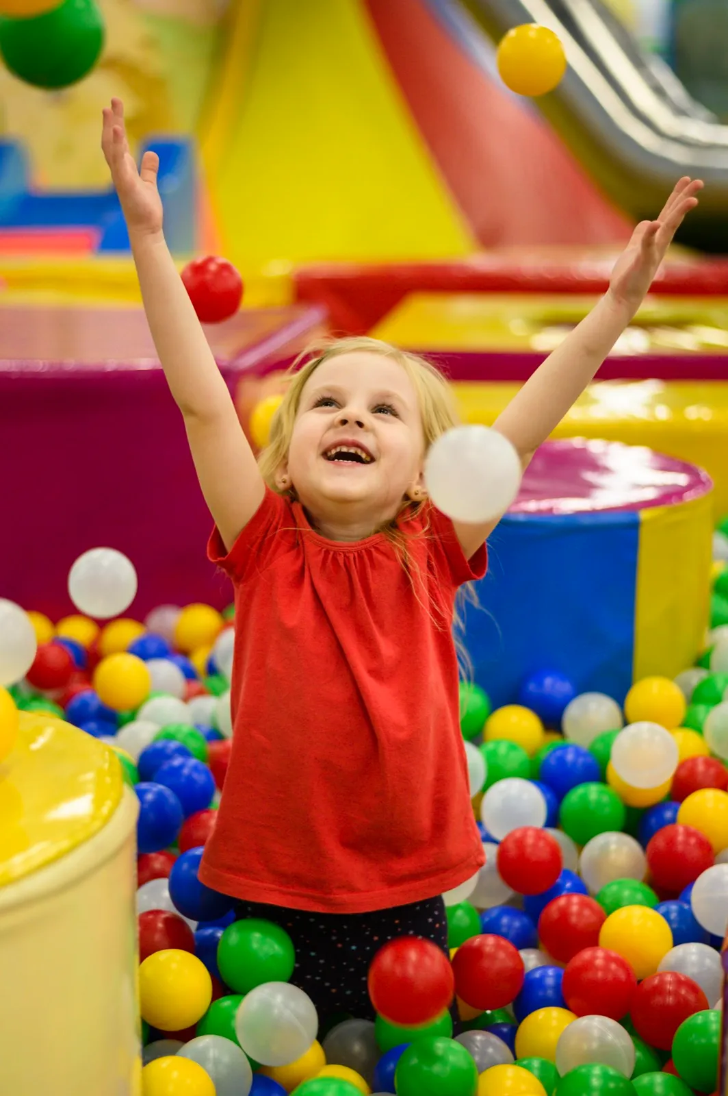 A child playing in a ball pit at a soft play area