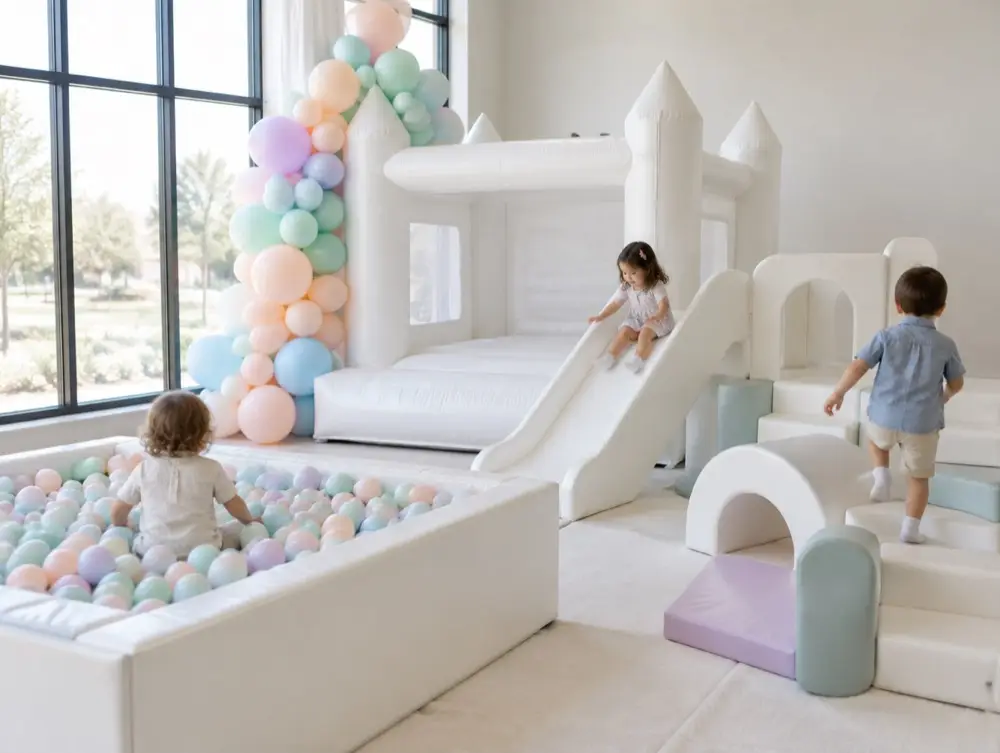 A white bounce castle with a slide, a pastel ball pit and kids playing