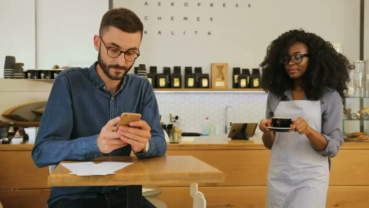 A customer looks at a menu on a phone in a café